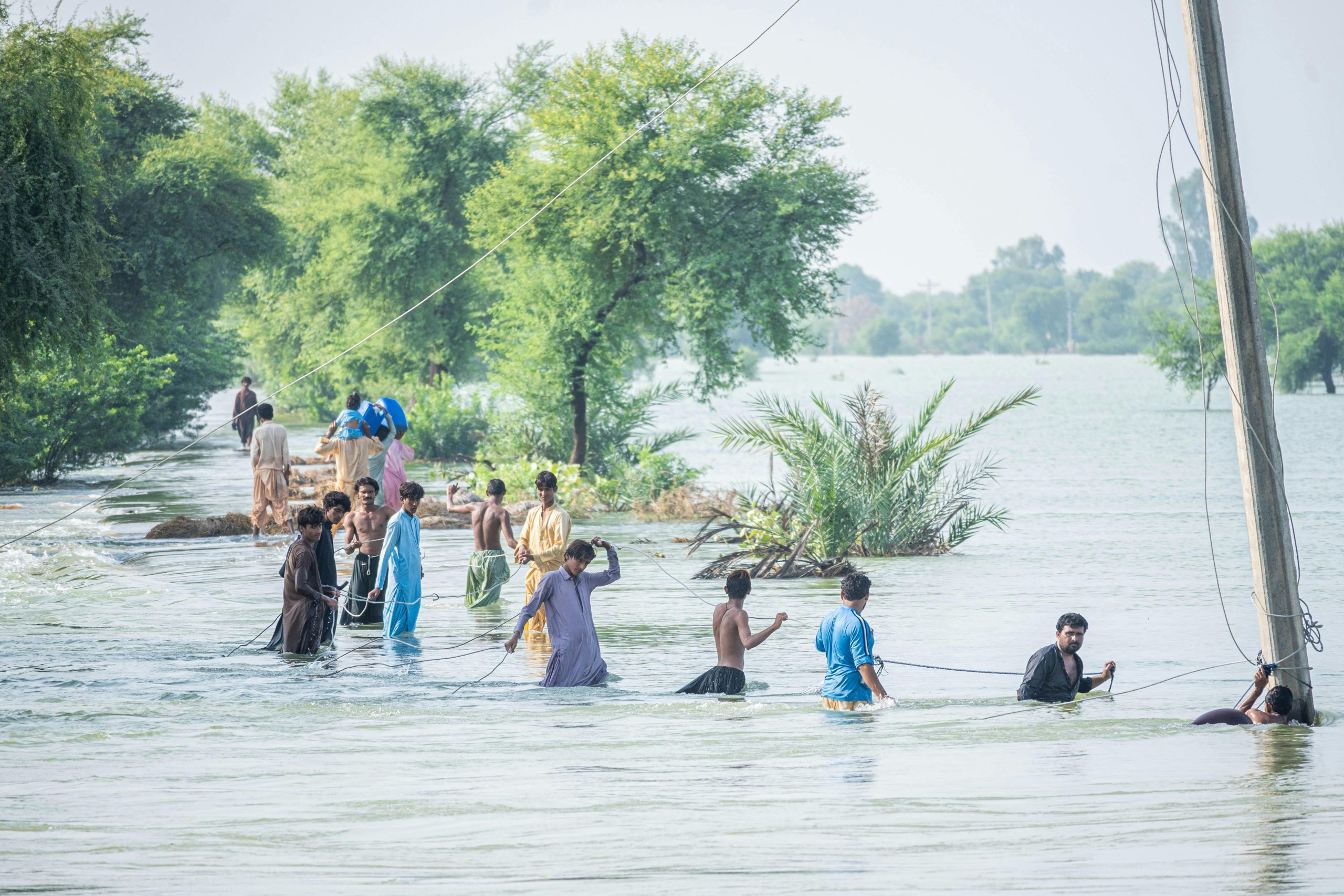 A group of men wading in flood waters in Pakistan